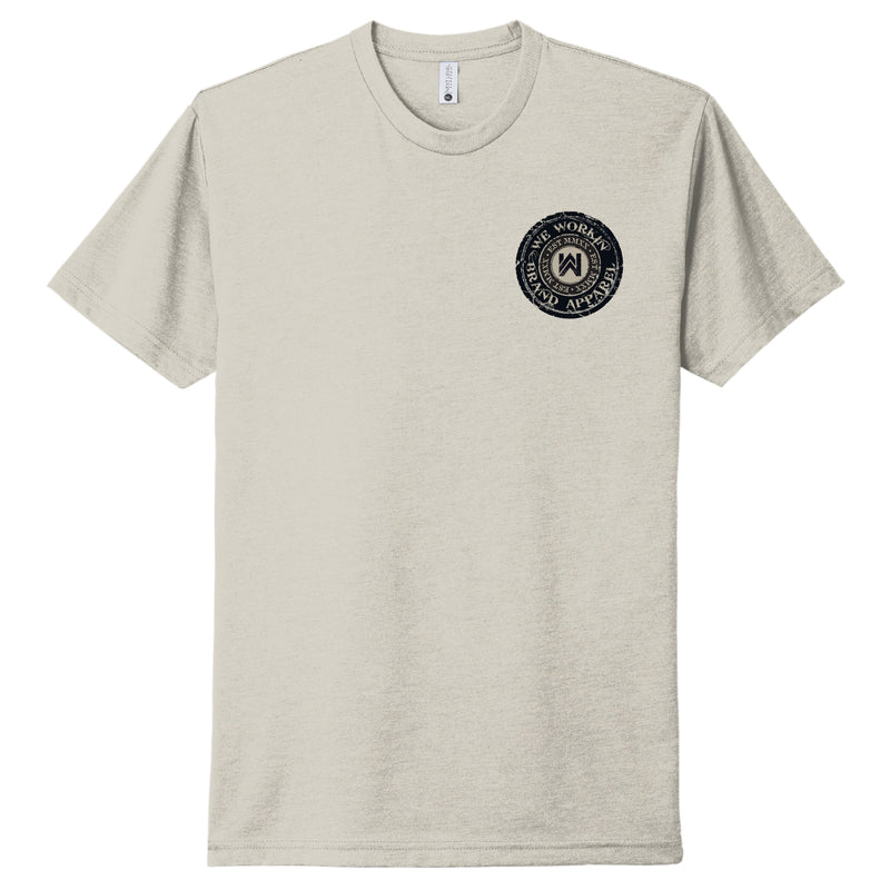 Front of a WW Sand color Graphic Tee. Circular graphic "WE WORKIN BRAND APPAREL" circular text and WW icon logo and EST MMXX smaller (also circular) inside the main text design in center of circular image. Printed small on the left chest "pocket" area in black ink.