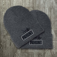 Two WW HUNT Dark Heathered Grey cuffed beanies on a grey tile background. Embroidered with WW HUNT and ELK image in our signature "patch" style on the folded cuff (WW icon/text/elk graphic in black thread, outer outline in black thread, inner "rope" in white thread). 