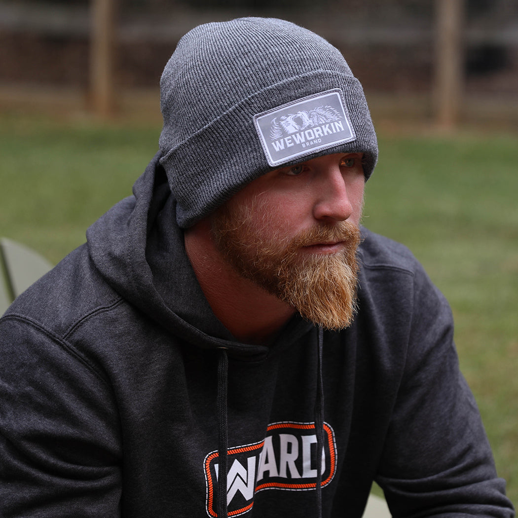 BEANIES Collection. Man pictured wearing a cuffed beanie in dark grey with grey patch and WW HARD charcoal Grey hoodie with Neon Orange ink.