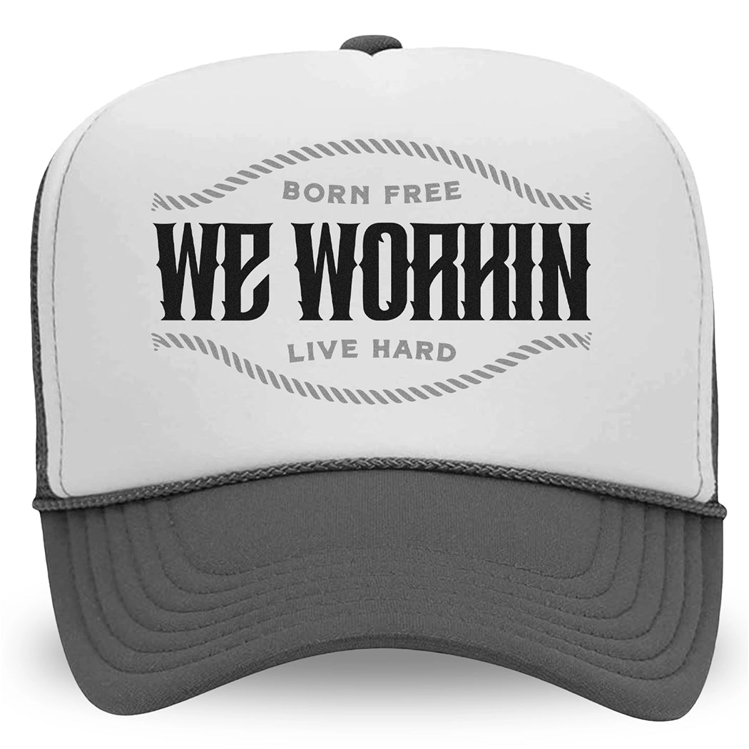 Foam Trucker hat in charcoal/grey colorway on white background. "WE WORKIN. BORN FREE—LIVE HARD" text design. 