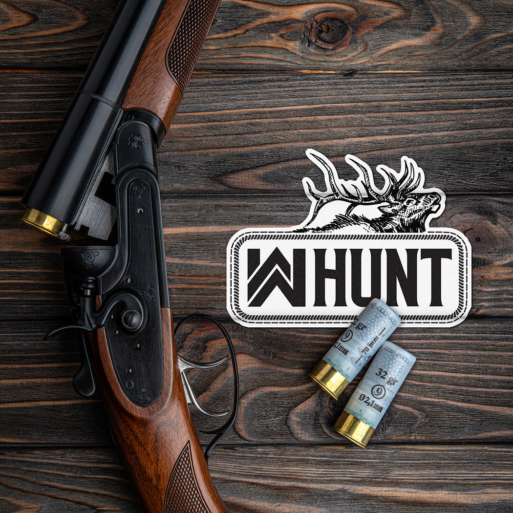 HUNT Collection. Shotgun and shells on a wooden background with a WW HUNT Black/White die cut sticker.