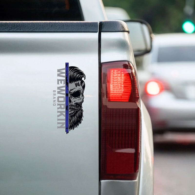 Cropped in image of a SMALL size WEWORKIN BRAND LEO Black/Blue/Grey Skull decal 7.375"H—Custom die-cut Direct Transfer window sticker, on tailgate (Right side) of a truck.