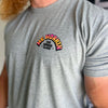 Man from front, wearing a WW heather grey tee. 3-color BARBELL CREW design in Neon Pink to Bright yellow fade and black, "WE WORKIN" main text is arched over top of "THE WORKIN CLASS" text (MM and XX roman numbers are on either side of middle text—design is printed small in the left "pocket" area of chest.