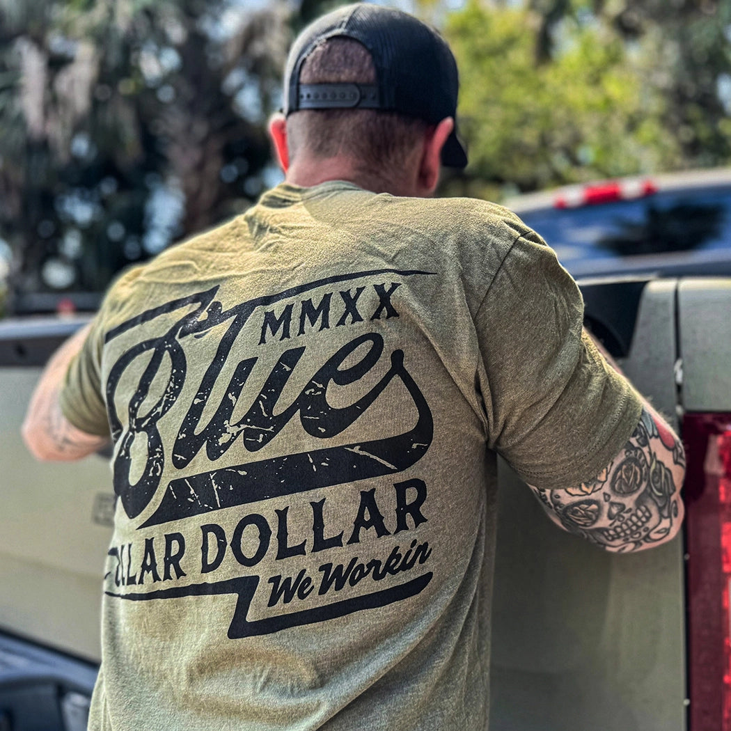 Man pictured from back, wearing a BCD Vintage WW military green tee. Blue Collar Dollar "Vintage" text graphic is printed large in the center/upper back area, in black ink.