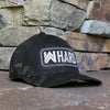 Front right view of Flexfit hat. MultiCam® black pattern fabric embroidered with WW HARD "patch" style across the front (WW HARD icon/text in white thread, outer outline in white thread, inner outline in grey thread). Front bill in MultiCam® black pattern.