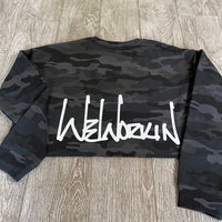 Back view of the We Workin women's lightweight cropped crew pullover in Black Camo (back print only, no front print). WEWORKIN Script logo is printed large across the back, bottom hem area in white ink. Imprint approx 13" wide.