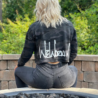 Woman pictured from back wearing a We Workin women's lightweight cropped crew pullover in Black Camo (back print only, no front print). WEWORKIN Script logo is printed large across the back, bottom hem area in white ink. Imprint approx 13" wide.