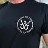 Man wearing a WW black tee, shown from front. BORN TO FISH—FORCED TO WORK text encircles fishing hooks and line (printed on the left chest "pocket" area.) Printed in White and Grey inks.