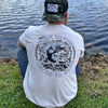 Man wearing a WW sand color tee, shown from back, sitting along a water bank. BORN TO FISH—FORCED TO WORK text encircles a graphic of Fish jumping out of water and bulldozer on land in the background. Printed in Black and Grey inks. Graphic is printed large on the centerback.