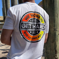 Man from back, wearing a WW white tee. 3-color Distressed circular Neon Yellow and Neon Orange design, "GET HARD" main text in center of layout, "WE WORKIN" and "Never Easy Always Worth It" on the top and bottom of circular design, and finally "Hard Workin" and "Hard Livin" in center top/bottom—printed large in the center/upper back.