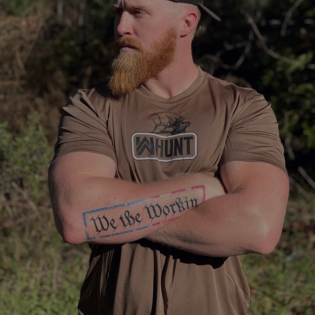 HUNT Collection. Man pictured from front outdoors in woods, wearing a WW HUNT Short Sleeve ultra lightweight tee in woodland brown, screen printed with our newest design, the WW HUNT "patch" style, with Elk, front and center on chest.