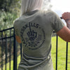 Woman pictured from back wearing a We Workin designed LAZINESS KILLS middle finger circular graphic on a military green fitted tee.
