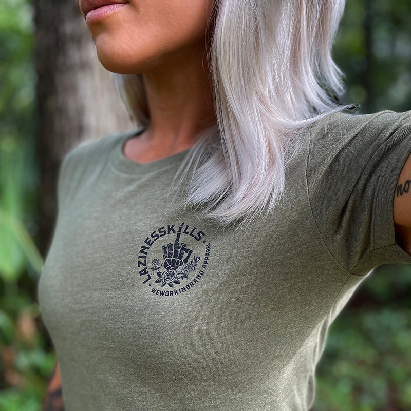 Woman pictured from front wearing a We Workin designed LAZINESS KILLS middle finger circular graphic on a military green fitted tee (design on "pocket" area).