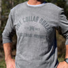 Man pictured from front wearing a WW Grey Frost colored long sleeve shirt. "BLUE COLLAR DOLLAR. Blood. Sweat. Profanity." arched graphic screen printed on the center chest in dark grey ink. Banded collar and cuffs. 