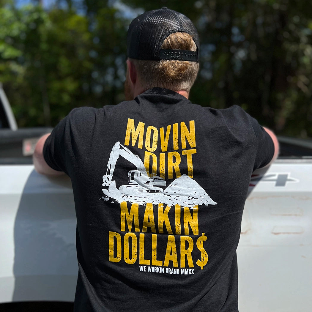 Man pictured from back, wearing a "MOVIN DIRT. MAKIN DOLLAR$." WW black tee. Distressed text with a track hoe movin dirt in the center. Graphic is printed large in the center/upper back, in gold and white ink.
