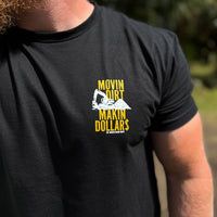 Man pictured from front wearing a "MOVING DIRT. MAKIN DOLLAR$." WW black tee. Distressed text with a track hoe movin dirt in the center. Graphic is printed smaller in gold and white ink, on the left "pocket" area.