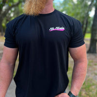 Man wearing a WW black tee, shown from front. "WE WORKIN" script text  with Neon Pink swashes under text, is printed on the left chest "pocket" area. Printed in White and Neon Pink inks.