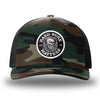 Green Camo/Black two-tone WeWorkin hat—Richardson 112PFP snapback, 5-panel trucker, mesh-back style. HARD WORK MATTERS woven patch with white merrowed edge, on a black background with HARD WORK MATTERS text encircling a Viking-style skull center graphic with MM XX on the left and right respectively—patch is centered on the front panels.