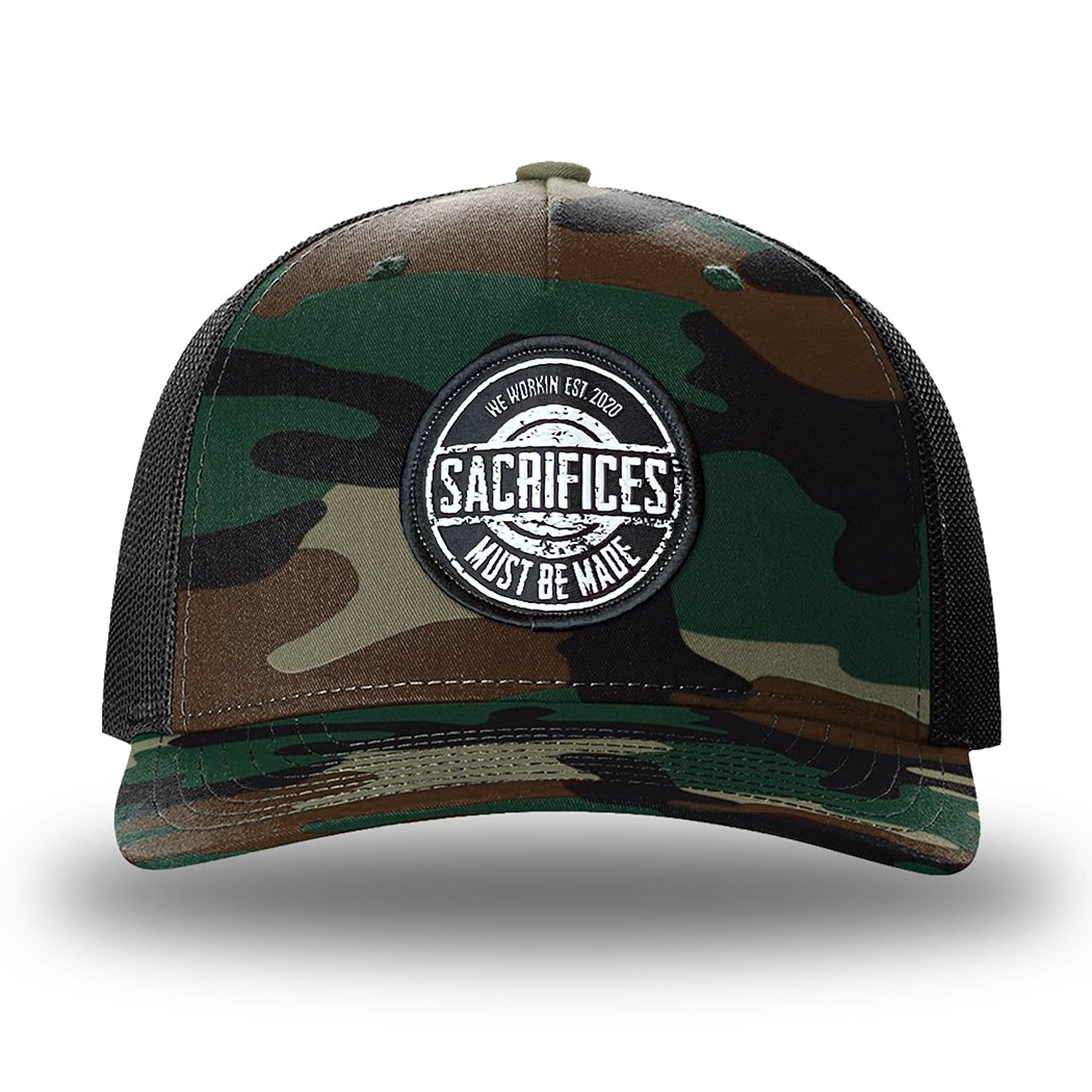 Green Camo/Black two-tone WeWorkin hat—Richardson 112PFP snapback, 5-panel trucker, mesh-back style. WeWorkin "SACRIFICES MUST BE MADE" circular woven patch is centered on the front panel.