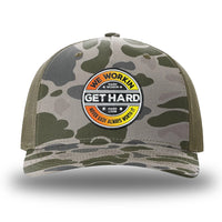 Marsh Duck Camo/Loden two-tone WeWorkin hat—Richardson 112PFP snapback, 5-panel trucker, mesh-back style. WE WORKIN custom GET HARD patch made of thermoplastic, lightweight, durable material is centered on the front panels in orange to yellow fade and black colors.