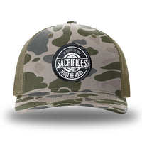 Marsh Duck Camo/Loden two-tone WeWorkin hat—Richardson 112PFP snapback, 5-panel trucker, mesh-back style. WeWorkin "SACRIFICES MUST BE MADE" circular woven patch is centered on the front panel.
