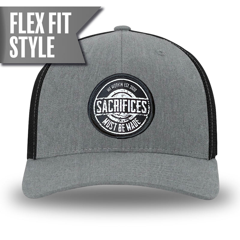 Heather Grey/Black Flex Fit style WeWorkin hat—Woven front with Poly mesh sides and back, Richardson 110 brand (R-Flex trucker). WeWorkin "SACRIFICES MUST BE MADE" circular woven patch is centered on the front panels.