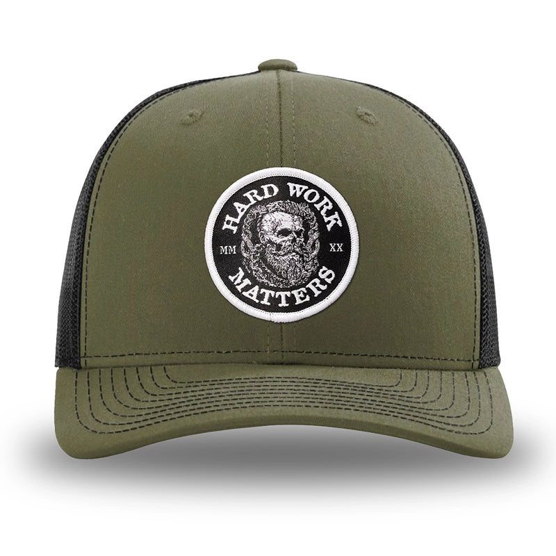 Loden/Black WeWorkin hat—Richardson 112 brand snapback, retro trucker classic hat style. HARD WORK MATTERS woven patch with white merrowed edge, on a black background with HARD WORK MATTERS text encircling a Viking-style skull center graphic with MM XX on the left and right respectively—patch is centered on the front panels.