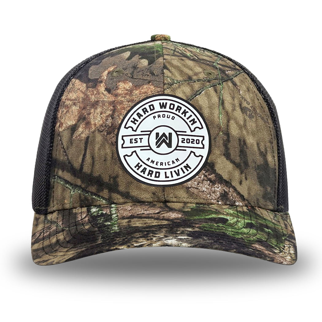 Mossy Oak/Country DNA/Black WeWorkin hat—Richardson 112 brand snapback, retro trucker classic hat style. "HARD WORKIN. HARD LIVIN." Proud American silicone circle patch is centered on the front panels.