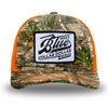 Neon Orange and RealTree Camo two-tone WeWorkin hat—Richardson 112 brand snapback, retro trucker classic hat style. BLUE COLLAR DOLLAR VINTAGE (BCD-V) woven patch with black merrowed edge, on a white background with black text, is centered on the front panels.