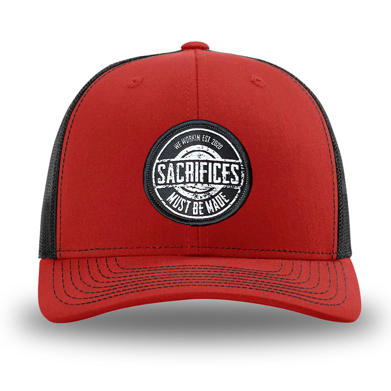 Red/Black WeWorkin hat—Richardson 112 brand snapback, retro trucker classic hat style. WeWorkin "SACRIFICES Must Be Made" circular woven patch, with black/white thread colors and black merrowed edge, is centered on the front panels.