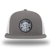 Charcoal/White WeWorkin hat—Richardson 511 brand snapback, flatbill trucker hat style. WeWorkin "SACRIFICES Must Be Made" circular woven patch, with black/white thread colors and black merrowed edge, is centered on the front panels.