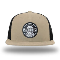 Khaki/Black WeWorkin hat—Richardson 511 brand snapback, flatbill trucker hat style. WeWorkin "SACRIFICES Must Be Made" circular woven patch, with black/white thread colors and black merrowed edge, is centered on the front panels.