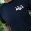 Man wearing a WW Black tee. Front pocket area imprint with "WE WORKIN. BLUE COLLAR COWBOY" text with stars on the top, printed small in grey and white inks.