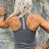 Woman pictured from back wearing a WEWORKIN racerback tank top in grey, with WEWORKIN BRAND logotype imprinted in white ink vertically on material between shoulder blades.