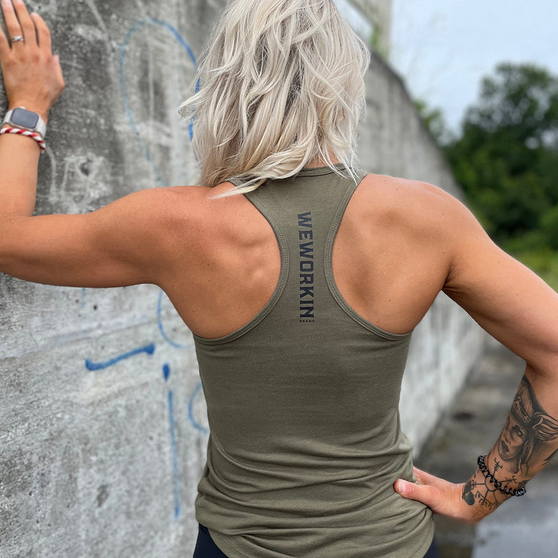 Woman pictured from back wearing a WEWORKIN racerback tank top in military green, with WEWORKIN BRAND logotype imprinted in black vertically on material between shoulder blades.