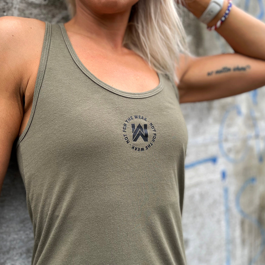 Woman pictured from front wearing a WEWORKIN racerback tank top in military green, front has the text "NOT FOR THE WEAK" encircling the WeWorkin icon on the chest, printed in black. 