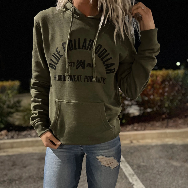 Woman wearing a We Workin Military Green hoodie with the "Blue Collar Dollar. Blood. Sweat. Profanity." arched graphic screen printed in black ink on the front. 