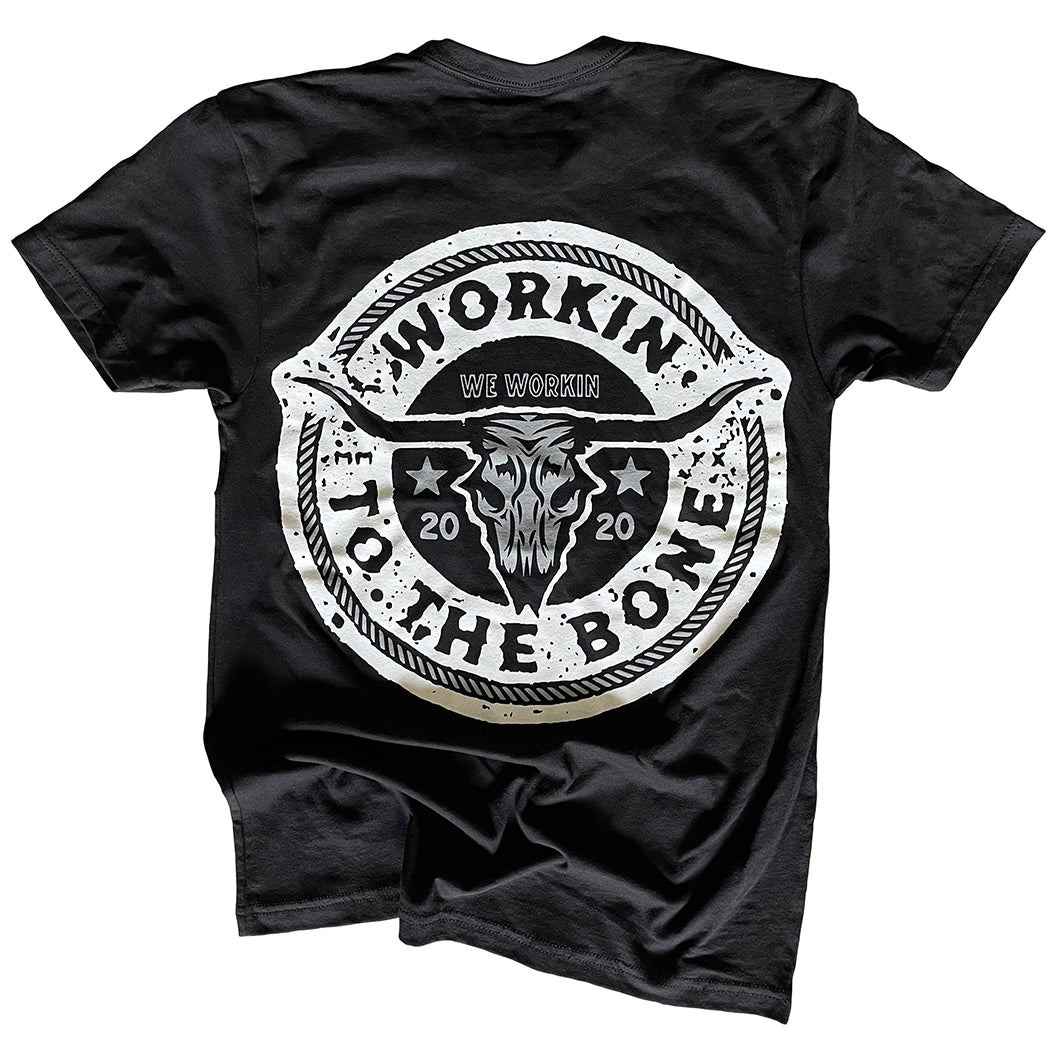 Back of a WW black tee on a white background. "WORKIN TO THE BONE" text circular graphic with a cow skull in the center is printed large in the center/upper back, in grey and white ink.