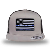 Silver/Black two-tone WeWorkin hat—snapback, 5-panel classic trucker, mesh sides/back style. We Workin LEO FLAG woven patch with black merrowed edge is centered on the front panel.
