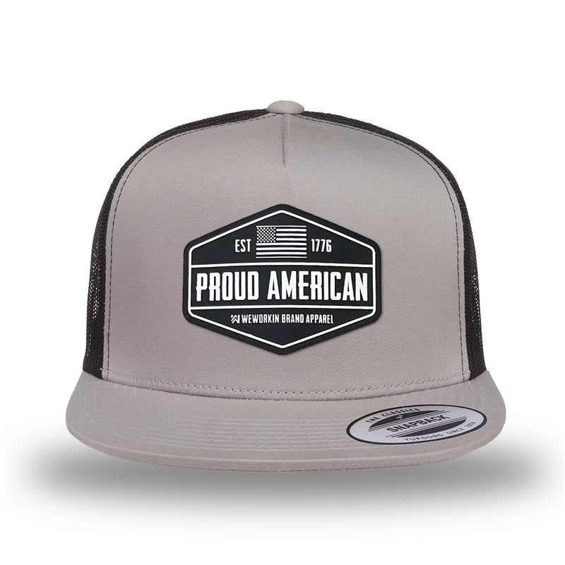 Silver/Black two-tone WeWorkin hat—snapback, 5-panel classic trucker, mesh sides/back style. WeWorkin "PROUD AMERICAN" silicone patch is centered on the front panel.
