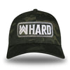 A Multicam® Black Flexfit hat on white background. Embroidered with WW HARD "patch" style across the front (WW HARD icon/text in white thread, outer outline in white thread, inner outline in gray thread). 