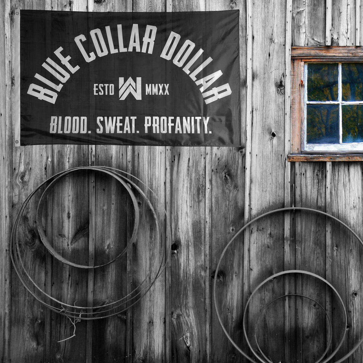 WeWorkin Brand "BLUE COLLAR DOLLAR—Blood. Sweat. Profanity." Arch-design flag hung on a barn wall. Each flag measures approx. 5'w x 3'h, black background with white letters. White, double-stitched, thicker left edge for durability, (2) grommets (one at top left and one at bottom left corners).