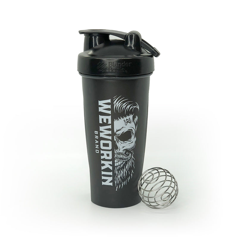 Black Classic BlenderBottle® with WeWorkin Brand icon vertically printed in white, large, on side. Wire whisk ball leaning against bottle. On white background.