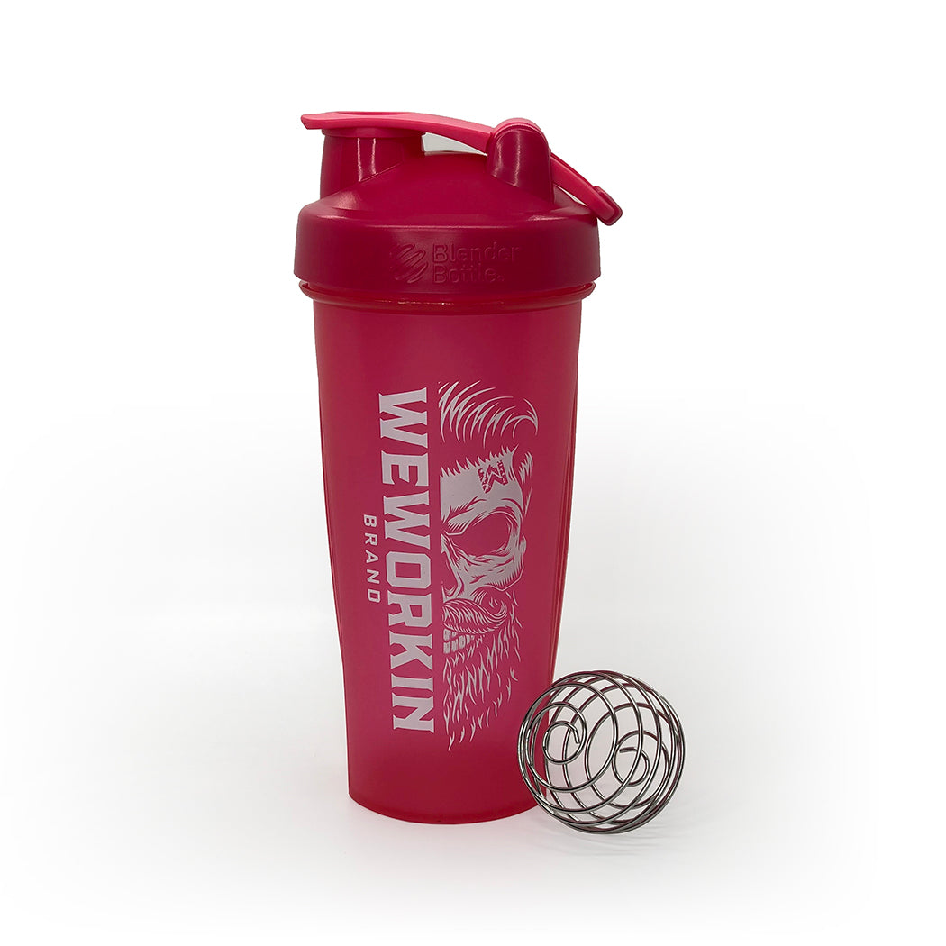 Bold Pink Classic BlenderBottle® with WeWorkin Brand icon vertically printed in white, large, on side. Wire whisk ball leaning against bottle. On white background.