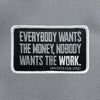 "EVERYBODY WANT$ THE MONEY, NOBODY WANTS THE WORK." text centered large on a velcro-backed patch (both the hook and loop sides provided). [2] thread colors for the design (medium grey and white) on a black woven background, with white merrowed border. 3.5" wide Woven patch displayed on a grey canvas background.