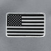 AMERICAN FLAG on a velcro-backed patch (both the hook and loop sides provided). [1] thread color for the stars and stripes (white) on a black woven background, with white merrowed border. 3.5" wide Woven patch displayed on a grey canvas background.