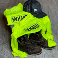 We Workin Hi-Viz long sleeve tees in Safety Yellow placed with workboots and We Workin Black Camo Retro Trucker snapback hat. Front of tee is printed with the We Workin WWHARD patch-style icon printed in Black ink, except the "rope" style outline is in grey ink.