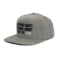 A WeWorkin Snapback Flat Bill Hat in light Heather Grey on white background, left-front side. "Everybody Wants the Money, Nobody Wants the WORK." is embroidered front and center in Black and White thread.