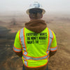 Man on a construction site, pictured from the back with a hard hat on, wearing the We Workin Class 3 Mesh Zippered Short Sleeve Vest. Back is printed with the WEWORKIN BRAND "Everybody Want$ the Money, Nobody Wants the WORK." slogan in black ink. (Front is blank)