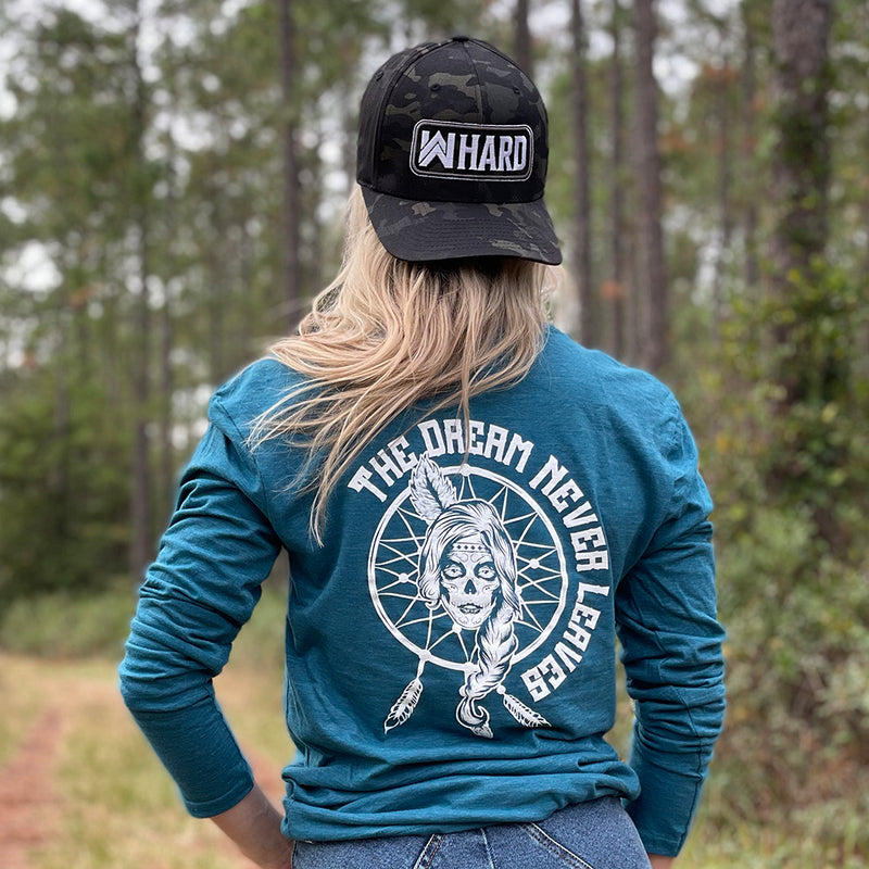 Woman pictured from back in heather teal long-sleeved tee, imprinted with the text "The Dream Never Leaves" and a dreamcatcher/indian graphic in white ink on full back. Also wearing a We Workin WW HARD black camo flexfit hat.